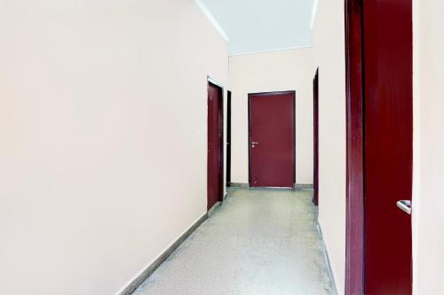 an empty corridor with red doors and a concrete floor at Super Hotel O GMS Road Ballupur Chowk in Dehradun