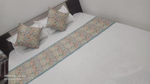 KhātuHotel Deepak place的一张带三个枕头的床和一条带子