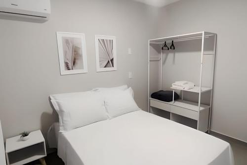 een witte slaapkamer met een wit bed en een spiegel bij Apto 2 qtos com wi-fi e garagem in Londrina