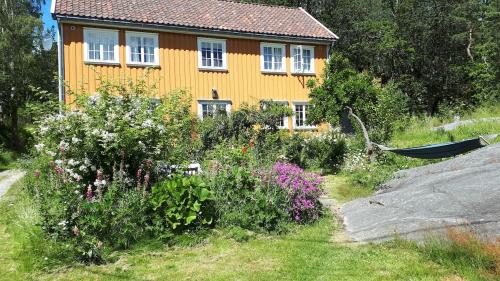a yellow house with a hammock in front of a garden at Large house with sea arch, beach and jetty in Lillesand