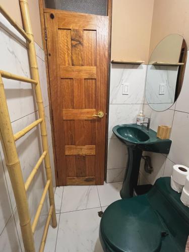 a bathroom with a green toilet and a wooden door at Cosy flat in the heart of Pisac with rooftop terrace in Pisac
