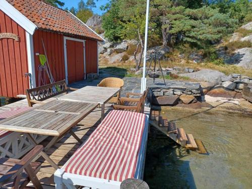 a wooden deck with a bench and a table at Large house with sea arch, beach and jetty in Lillesand