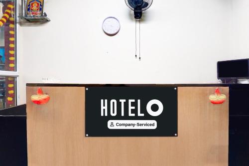 a sign for a hotel and a clock on a wall at Super Hotel O Laxmi Chowk Hinjewadi in Pune