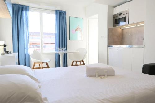 - une chambre avec un lit blanc, une table et des chaises dans l'établissement Escapade Urbaine - Studio Lumineux proche gare, à Lyon