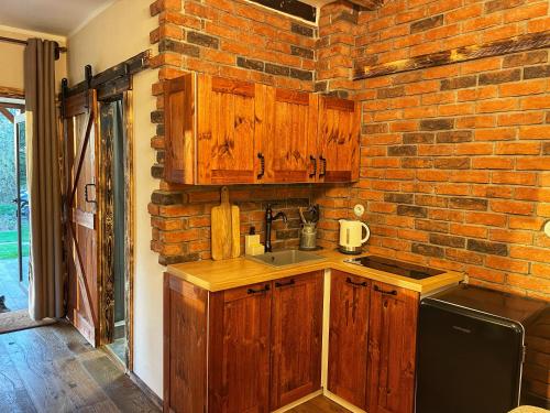 a kitchen with wooden cabinets and a brick wall at Trapani house & camp in Růžová