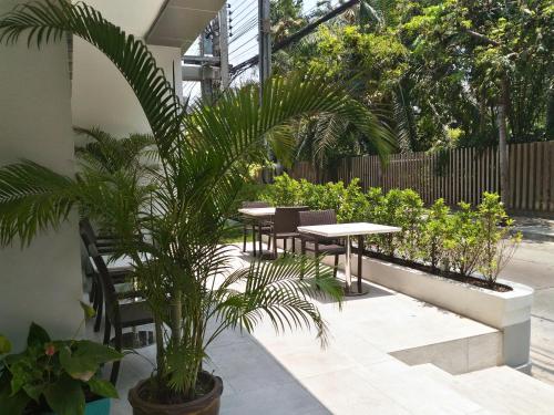 a patio with tables and chairs and a palm tree at Le Tada Residence in Bangkok