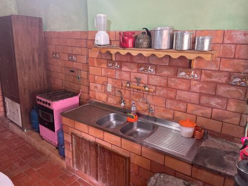 a kitchen with a sink and a brick wall at Igatu CENTRO in Andaraí