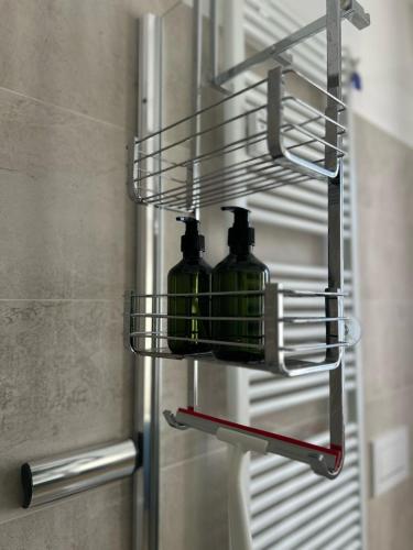 two green glass bottles in a metal rack in a bathroom at The VIEW - Spacious modern apt in Como