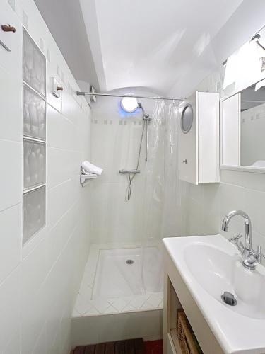 une salle de bain blanche avec un lavabo et une douche dans l'établissement Les Fleurs, à Cannes