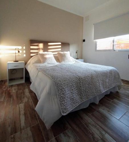 a bedroom with a large bed with a wooden floor at La Merced Areco Cabañas in San Antonio de Areco