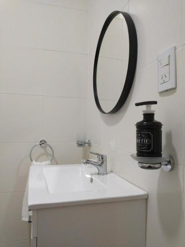 a white bathroom with a sink and a mirror at La Merced Areco Cabañas in San Antonio de Areco