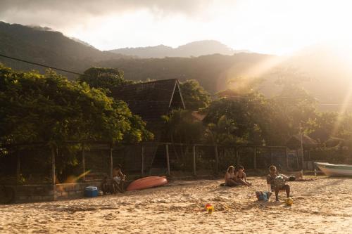 a group of people sitting on a beach at MAMBEMBE hostel - Ilha Grande, Vila do Abraão in Abraão