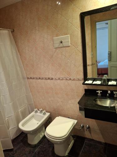 a bathroom with a toilet and a sink and a mirror at Novel Hotel in Buenos Aires