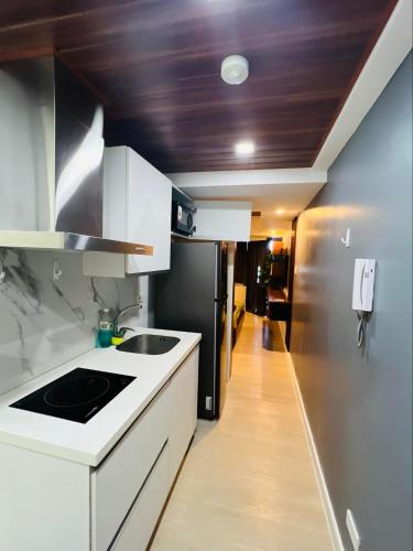 a kitchen with white cabinets and a black refrigerator at 22nd-Floor Spacious Studio with Sunrise & Pool Views, Hi-Speed WiFi & Working Space, Netflix, Disney, Kitchen, Wide Balcony in San Fernando