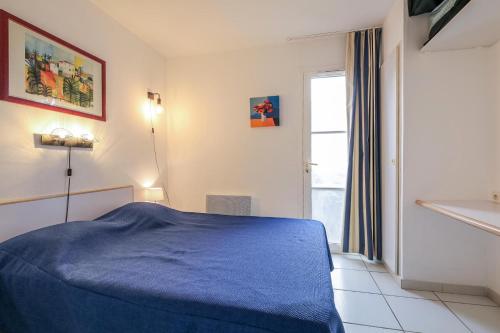 une chambre avec un lit bleu et une fenêtre dans l'établissement Résidence le Village de Cap Esterel - maeva Home - Appartement 2 pièces 4 personnes - Sans piscine - Sélection MAE-1941, à Saint-Raphaël
