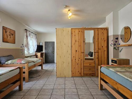 a bedroom with two beds and a wooden closet at App-O1-2-3-Personen-23km-bis-Frankfurt-Nord in Ober-Mörlen