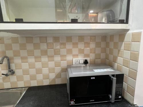 a kitchen with a microwave on a tiled wall at Atlas Homes 1BHK HomeStays in Hyderabad