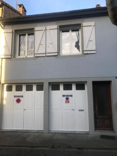 a white house with four white garage doors at APPARTEMENT F3 BOX Vélo Moto Centre historique in Mirepoix