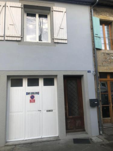 two white garage doors on a white building at APPARTEMENT F3 BOX Vélo Moto Centre historique in Mirepoix