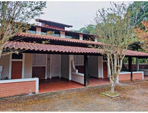 a house with a red roof and a tree at Quintal da Serra - Hospedagem in Barra do Piraí
