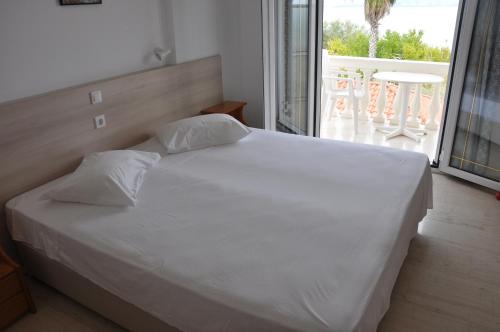 a bedroom with a large white bed with a balcony at neptune resort apartments in Kavos