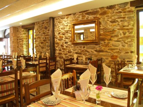 a restaurant with wooden tables and a stone wall at Hotel Vall d´Aneu in Esterri d'Àneu