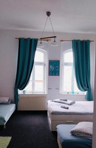 a bedroom with two beds and blue curtains at Art HOTEL in Chomutov