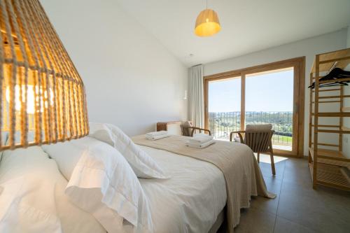 a bedroom with a white bed with a large window at OSTALEA Casa Rural in Villanueva de Alcolea