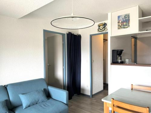 a living room with a blue couch and a table at Résidence Balcons Du Soleil 1 - T2/4pers BALCONS DU SOLEIL 12-Peyresourde MAE-9954 in Germ