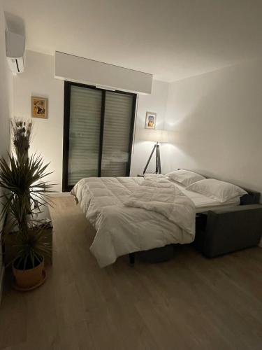 une chambre avec un lit et une plante en pot dans l'établissement Studio de vacances paisible et central, à Mandelieu-la-Napoule