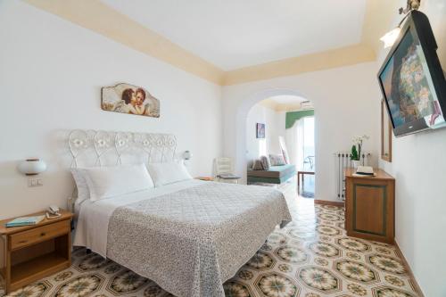 a white bedroom with a bed and a tv at Hotel Il Gabbiano in Positano