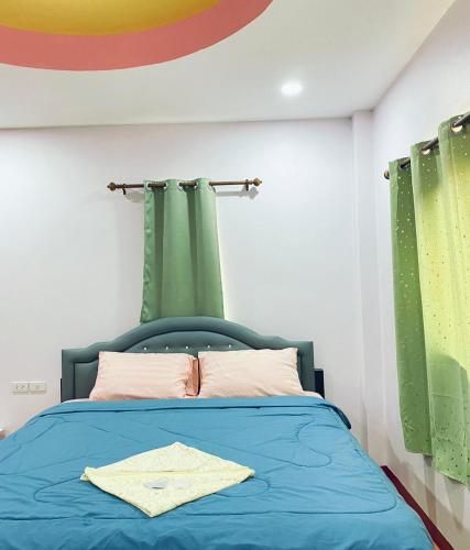 a bedroom with a blue bed with green curtains at ที่พักธารารักเลย ภูกระดึง in Ban Huai Som