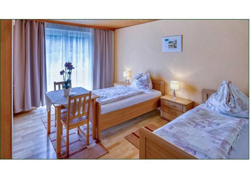 a hotel room with two beds and a table and a window at Frühstücks Pension Ebner-Hollerer in Übelstein