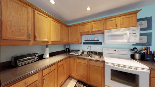 a kitchen with wooden cabinets and white appliances at Driftwood Landing 14 in Naples