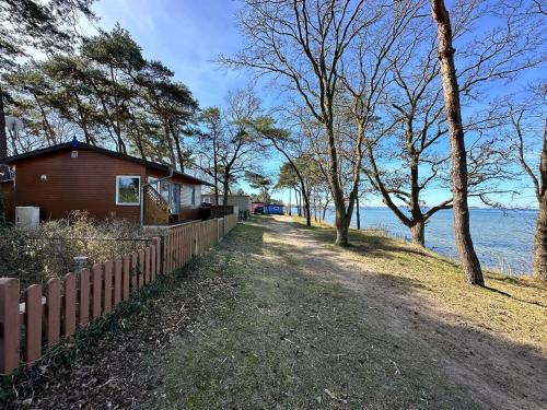 una casa con una valla junto al agua en Surf-Bungalow in erster Reihe, en Klein Strömkendorf