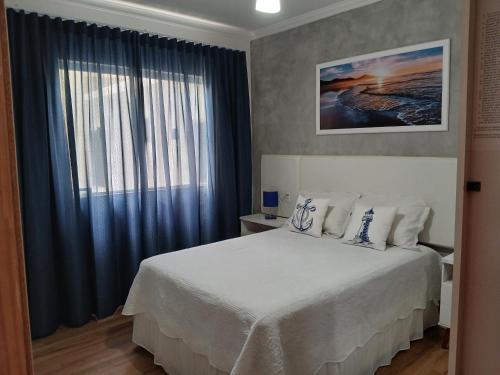 a bedroom with a bed with blue curtains and a window at Elegante Duplex Oceanico da Elena Super Cozinha USP y UfSCAR in São Carlos