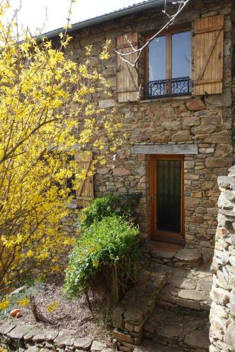 une maison en pierre avec une porte et des fenêtres en bois dans l'établissement Les jardins de Montaland, à Sainte-Catherine-sur-Riverie