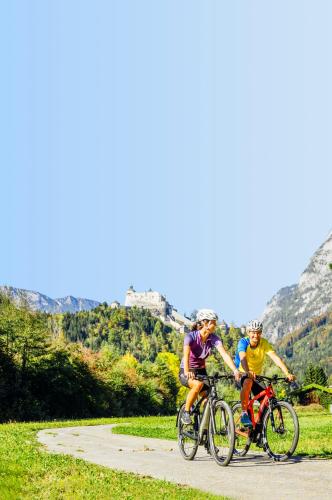 two people riding bikes down a road with mountains in the background at dorfwerfen137 in Pfarrwerfen