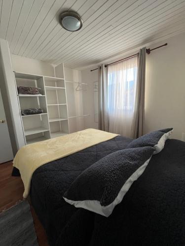 a bedroom with a black bed with a window at Cabañas Campestres Inés in Chillán