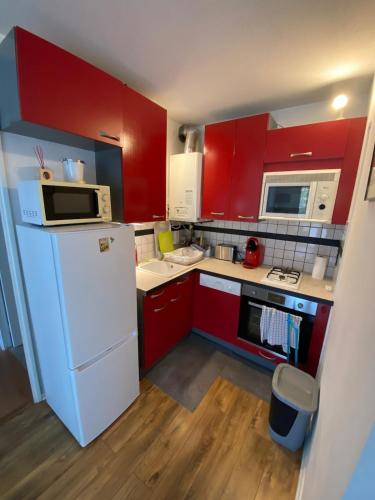Elle comprend une petite cuisine avec des placards rouges et un réfrigérateur blanc. dans l'établissement Totally Cosy place - 3 people - 600 m de la plage, à Arcachon