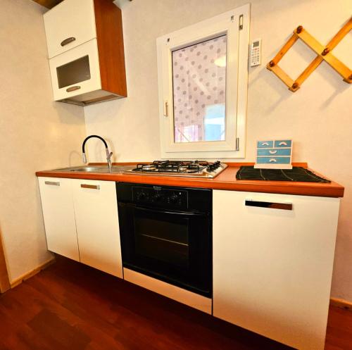 a kitchen with a stove and a sink and a window at LA CASA DEL SOLE in Merone