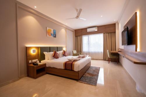 a hotel room with a bed and a desk at Hotel Grand Ajantha in Putuppalli