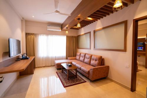 a living room with a leather couch and a table at Hotel Grand Ajantha in Putuppalli