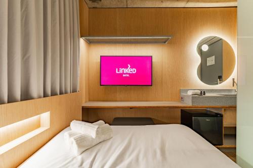 a room with a bed and a tv on a wall at Linked Batel by Xtay - Experiencia moderna a passos do Hard Rock in Curitiba