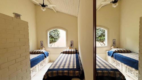two beds in a room with two windows at Recanto da Paz Tur - Relax e charme na serra in Miguel Pereira