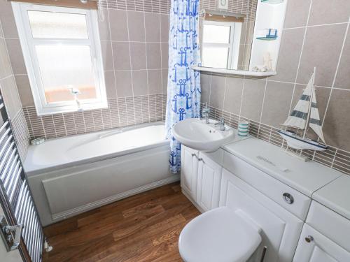 a bathroom with a sink and a toilet and a bath tub at Heddwch in Stepaside