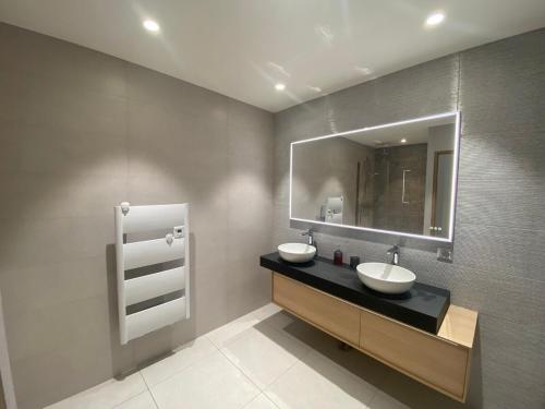 une salle de bain avec deux lavabos et un miroir dans l'établissement Les Ricochets, à Coutenson