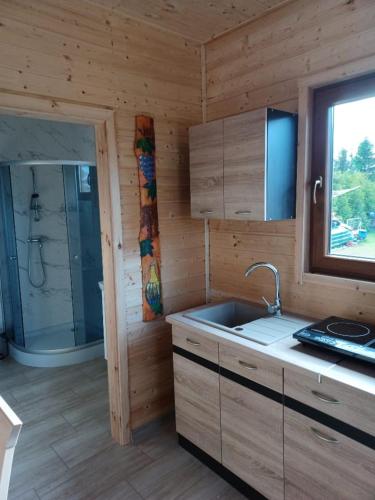 a kitchen with a sink and a shower in a cabin at Domki Pod Brzozami in Sarbinowo
