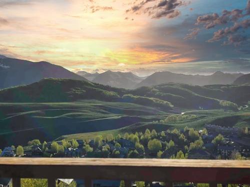 クレスティド・ビュートにある3BR Mountain Condo at the Trailhead with Huge Viewsの木製のベンチ付きの山の谷に沈む夕日