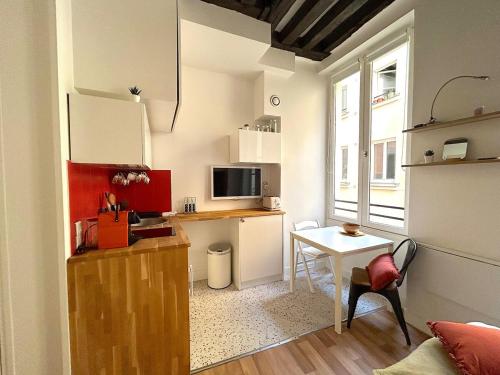 Il comprend une petite cuisine avec une table et une petite cuisine avec un bureau. dans l'établissement Large studio - heart of Paris, à Paris